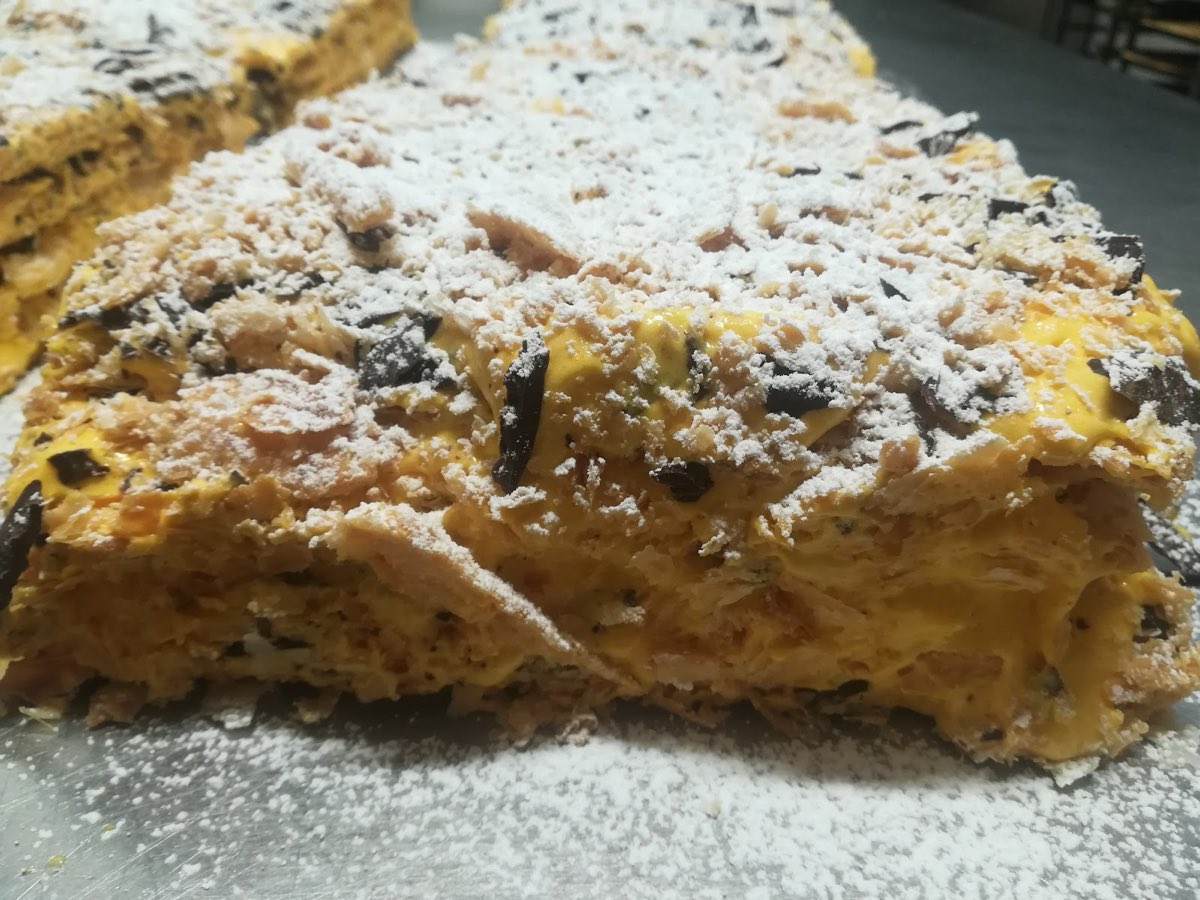Una fetta di dolce con crema e cioccolato, spolverata di zucchero a velo